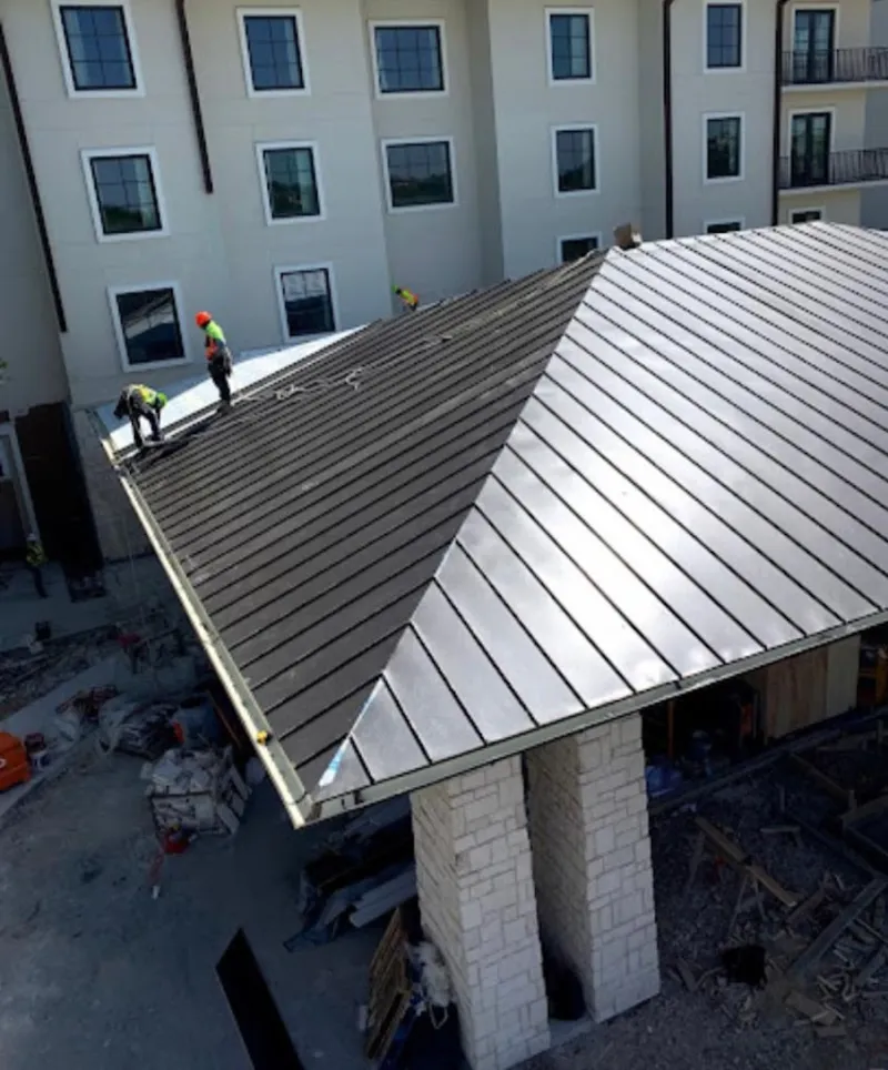 Crew installing standing seam metal roof panels on a commercial project in Pine Hills